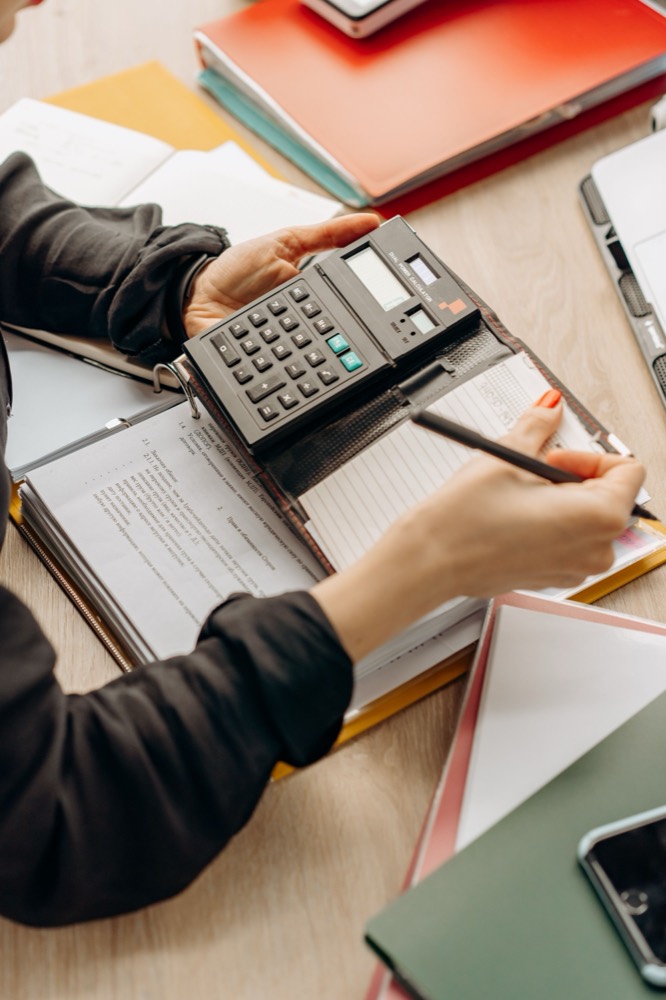 Rotina financeira sendo organizada com calculadora e documentos